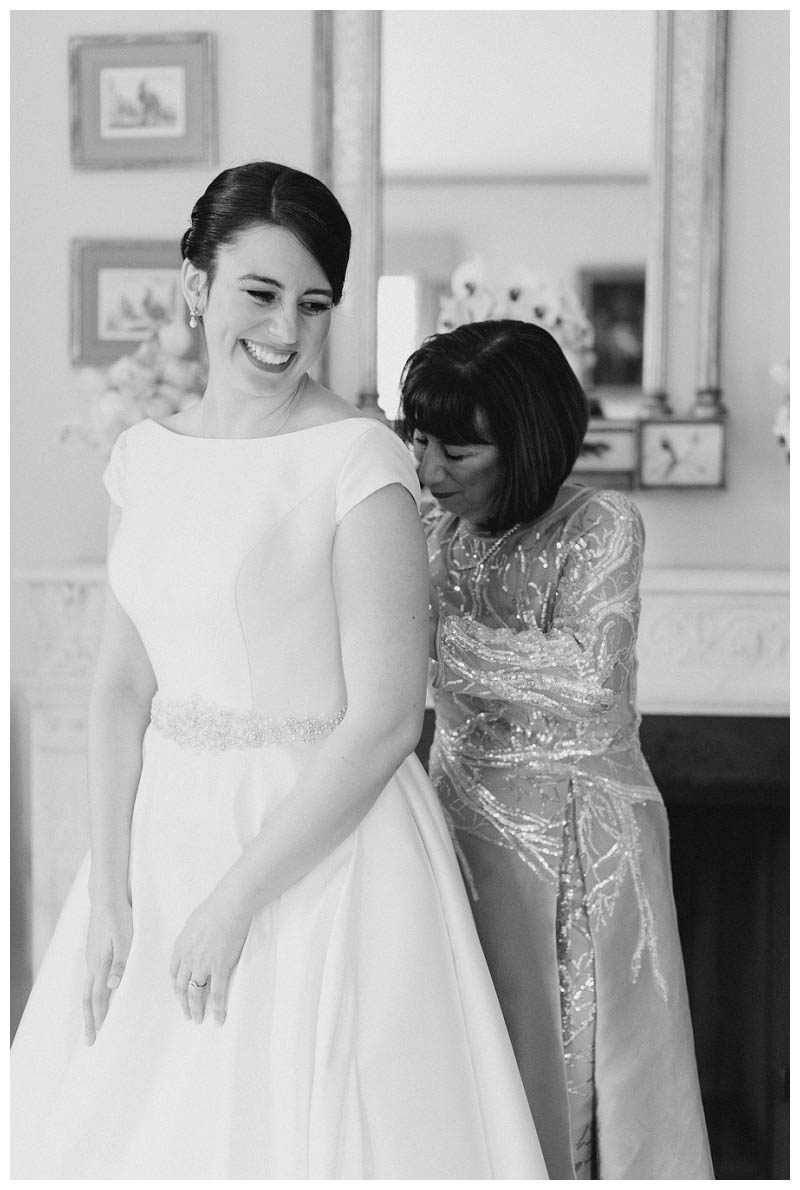 bride putting on wedding dress with mother