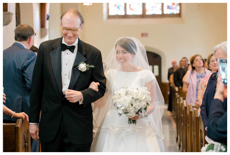 Happy bride walking down aisle with father on wedding day