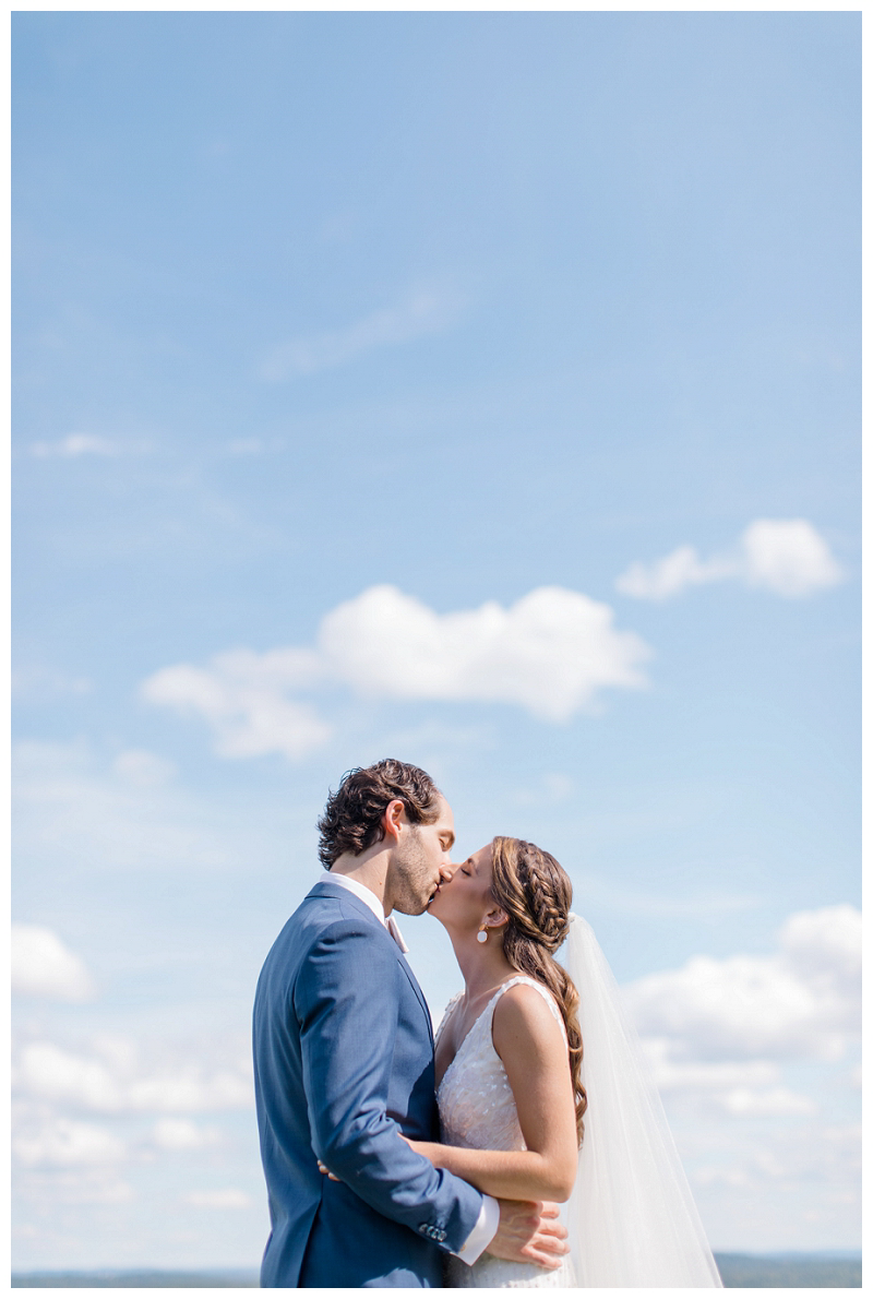bride and groom kiss in blue sky wedding photo